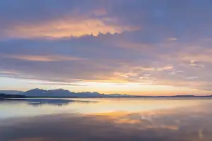 Sunset sky mirrored over calm water, symbolizing a dual funeral service ceremony