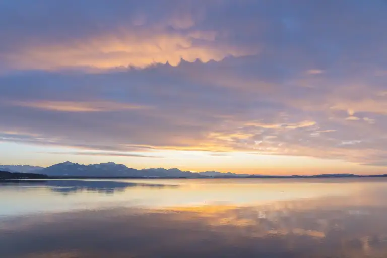 Sunset sky mirrored over calm water, symbolizing a dual funeral service ceremony